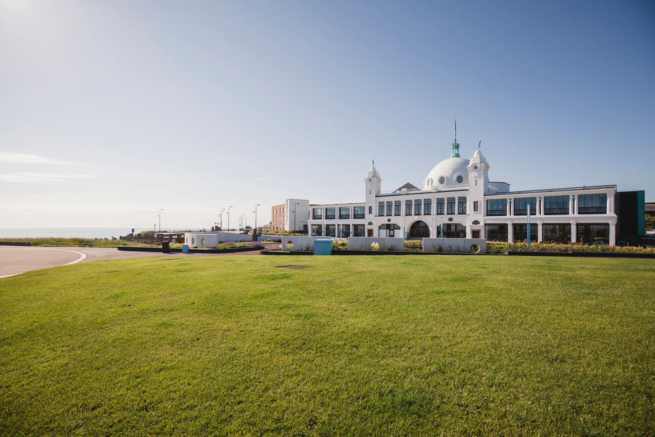 Large white coastal hotel building under blue sky